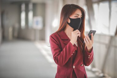 Maske takan ve cep telefonuyla konuşan Asyalı bir kadın PM2.5 'u korumak ve Covid-19 virüsü salgını yüzünden öksürüp duruyor..