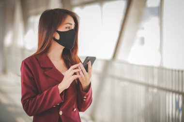 Maske takan ve cep telefonuyla konuşan Asyalı bir kadın PM2.5 'u korumak ve Covid-19 virüsü salgını yüzünden öksürüp duruyor..