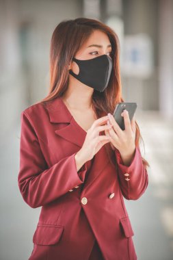 Maske takan ve cep telefonuyla konuşan Asyalı bir kadın PM2.5 'u korumak ve Covid-19 virüsü salgını yüzünden öksürüp duruyor..