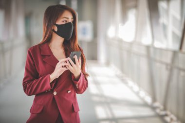 Maske takan ve cep telefonuyla konuşan Asyalı bir kadın PM2.5 'u korumak ve Covid-19 virüsü salgını yüzünden öksürüp duruyor..