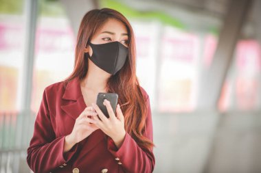 Maske takan ve cep telefonuyla konuşan Asyalı bir kadın PM2.5 'u korumak ve Covid-19 virüsü salgını yüzünden öksürüp duruyor..