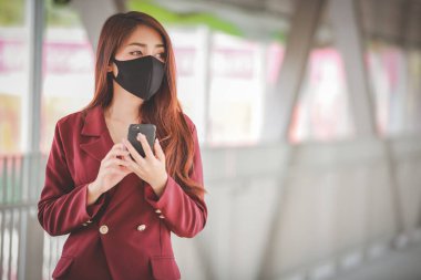 Maske takan ve cep telefonuyla konuşan Asyalı bir kadın PM2.5 'u korumak ve Covid-19 virüsü salgını yüzünden öksürüp duruyor..