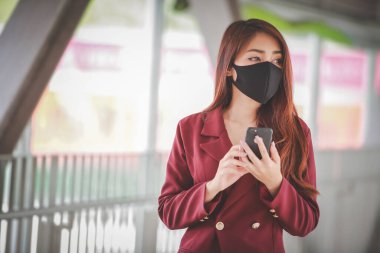 Maske takan ve cep telefonuyla konuşan Asyalı bir kadın PM2.5 'u korumak ve Covid-19 virüsü salgını yüzünden öksürüp duruyor..