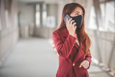 Maske takan ve cep telefonuyla konuşan Asyalı bir kadın PM2.5 'u korumak ve Covid-19 virüsü salgını yüzünden öksürüp duruyor..