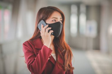 Maske takan ve cep telefonuyla konuşan Asyalı bir kadın PM2.5 'u korumak ve Covid-19 virüsü salgını yüzünden öksürüp duruyor..