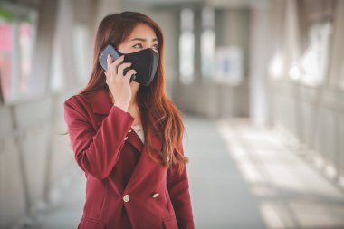 Maske takan ve cep telefonuyla konuşan Asyalı bir kadın PM2.5 'u korumak ve Covid-19 virüsü salgını yüzünden öksürüp duruyor..