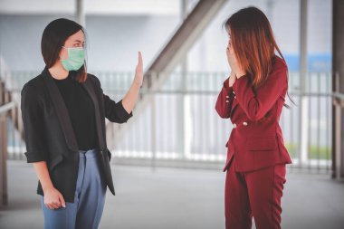 Kadın endişeli ve korku dolu. Dışarıdaki medikal maskeli bayan arkadaş öksürüyor. Mesafeyi koru Corona virüsünü durdur.