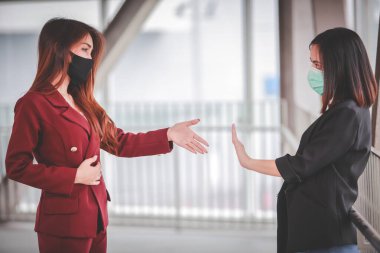 İki Asyalı kadın el ele tutuşmadan selamlaşmaktan kaçınıyor. Enfeksiyonu ve Covid-19 salgınını önlüyor..