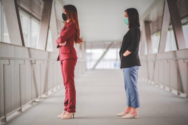 Diğer insanlardan 1 metre uzakta duran iki Asyalı kadın COVID-19 virüslerinden ve enfeksiyon riskine karşı sosyal mesafeyi koruyorlar..