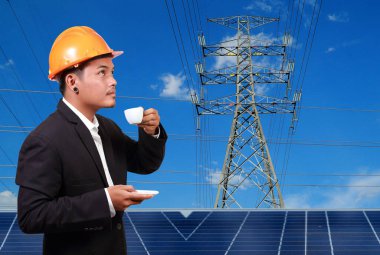 Yüksek voltaj kulelerine karşı güneş paneli olan mühendis..