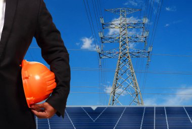 Yüksek voltaj kulelerine karşı güneş paneli olan mühendis..