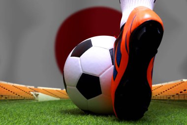 Futbol oyuncusunun bacakları ve ayakları kapalı yeşil çimlerin üzerinde yürür ve ulusal Japonya bayrağının arka planında maç yapmaya hazırdır..
