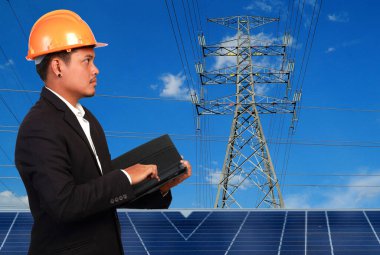 Yüksek voltaj kulelerine karşı güneş paneli olan mühendis..