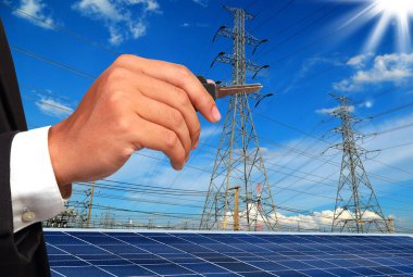 Şehrin arka planında elektrik kutupları ve güneş panelleri olan tanınmayan kişi