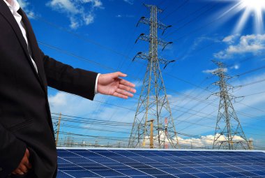 Şehrin arka planında elektrik kutupları ve güneş panelleri olan tanınmayan kişi