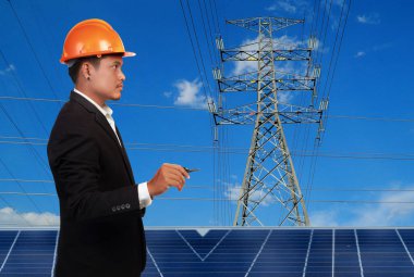 Yüksek voltaj kulelerine karşı güneş paneli olan mühendis..