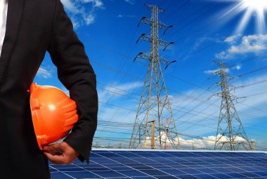 Şehrin arka planında elektrik kutupları ve güneş panelleri olan tanınmayan kişi