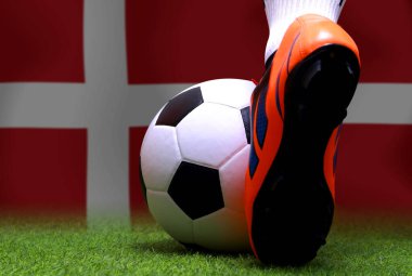 Futbolcunun bacakları ve ayakları kapalı yeşil çimlerde yürür ulusal Danimarka bayrağı arka planında maça hazırlanır.