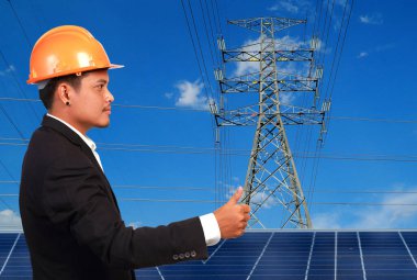 Yüksek voltaj kulelerine karşı güneş paneli olan mühendis..