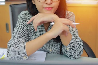 İş yerindeki gözlüklü güzel iş kadınının portresi. Ofisinde otururken yanında belgeler, not defterleri, akıllı telefonlar ve diğer malzemelerle..