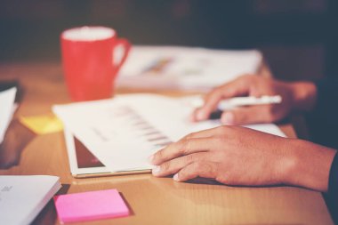 Ofis çalışanları ofis masasında bitmemiş belgelerin dökümanlarını düzenliyor. Bir yığın iş kağıdı ve turuncu ışık var.. 