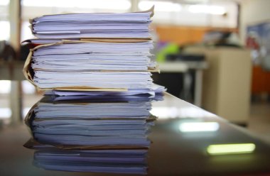 Ofis masası arşivine istiflenmiş tamamlanmamış kağıt işleri belgeleri piyasanın arşivinde inceleniyor ve gelecekte masa ofisinin ne kadar kar getireceğine karar veriliyor..