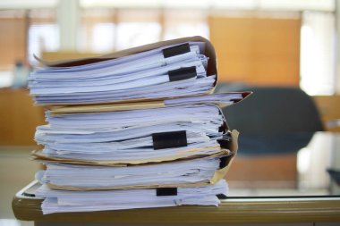 Ofis masası arşivine istiflenmiş tamamlanmamış kağıt işleri belgeleri piyasanın arşivinde inceleniyor ve gelecekte masa ofisinin ne kadar kar getireceğine karar veriliyor..