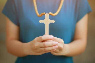 Yakın plan ahşap haç elinde Tanrı 'nın güneş ışığı arka planında çapraz kutsamasına odaklanmış, umut kavramı..