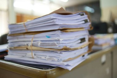 Ofis masası arşivine istiflenmiş tamamlanmamış kağıt işleri belgeleri piyasanın arşivinde inceleniyor ve gelecekte masa ofisinin ne kadar kar getireceğine karar veriliyor..