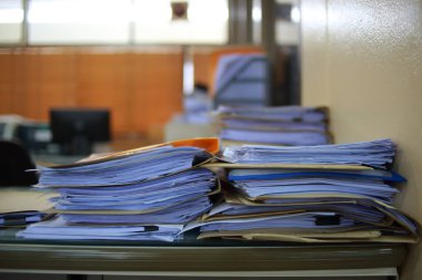 Ofis masası arşivine istiflenmiş tamamlanmamış kağıt işleri belgeleri piyasanın arşivinde inceleniyor ve gelecekte masa ofisinin ne kadar kar getireceğine karar veriliyor..