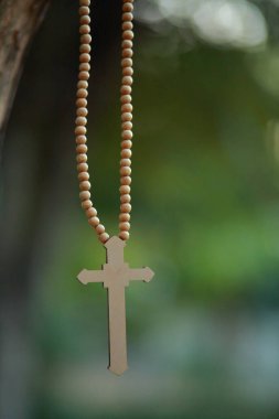 Yakın plan ahşap haç elinde Tanrı 'nın güneş ışığı arka planında çapraz kutsamasına odaklanmış, umut kavramı..