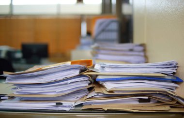 Ofis masası arşivine istiflenmiş tamamlanmamış kağıt işleri belgeleri piyasanın arşivinde inceleniyor ve gelecekte masa ofisinin ne kadar kar getireceğine karar veriliyor..