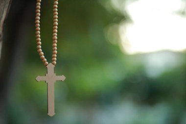 Yakın plan ahşap haç elinde Tanrı 'nın güneş ışığı arka planında çapraz kutsamasına odaklanmış, umut kavramı..