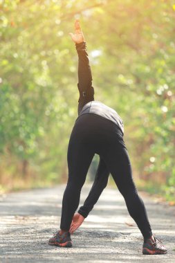 Yazın sonunda ya da sonbaharda ormanda güneş ışığı yolu ile koşmadan önce kaslarını ısıtır. fitness sağlıklı yaşam tarzı konsepti.