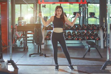 Güzel Asyalı kadın, bisepsler için çalışarak el egzersizi yapıyor. Ekipman kullanıyor..