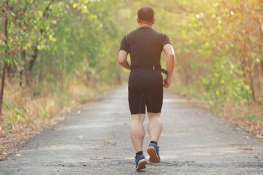 Spor koşucusu yaz sonunda ya da sonbaharda güneş ışığı yolu olan ormanda koşuya hazırlanıyor..