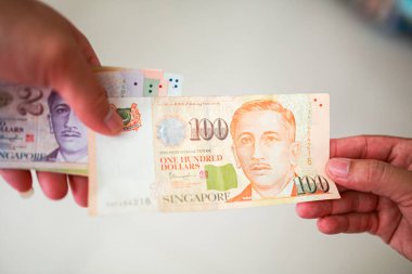 El ele tutuşan 10 Singapur dolarlık banknot alışverişe hazır, Singapur parası alışveriş için çok değerli..