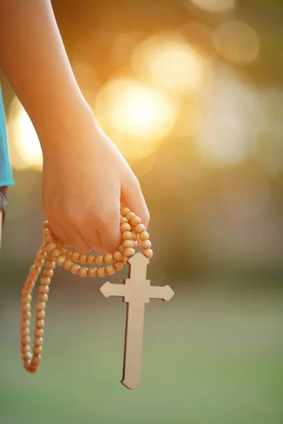 Close-up wooden cross in the hand with focus on the cross blessing from god on sunlight background, hope concept.