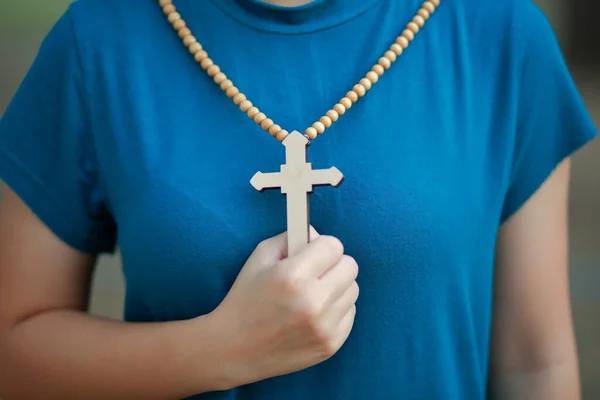 Close-up wooden cross in the hand with focus on the cross blessing from god on sunlight background, hope concept.