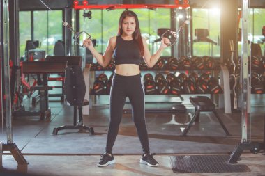 Bisepslerde ekipman kullanarak el egzersizi yapan sevimli Asyalı kadın. Ayarlanmış.