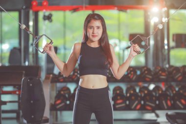 Bisepslerde ekipman kullanarak el egzersizi yapan sevimli Asyalı kadın. Ayarlanmış.