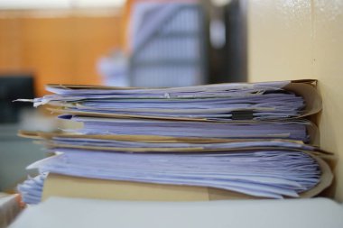 Ofis masası arşivine istiflenmiş tamamlanmamış kağıt işleri belgeleri piyasanın arşivinde inceleniyor ve gelecekte masa ofisinin ne kadar kar getireceğine karar veriliyor..