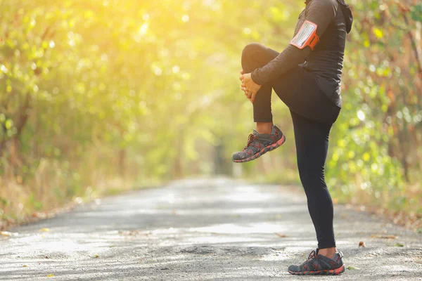 The man warms up muscles before jogging in forest with sunlight path in late summer or fall. fitness healthy lifestyle concept.