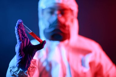 Bilim adamı laboratuarda renk tonu efekti üzerine sıvı dolu bir test tüpü tutuyor..