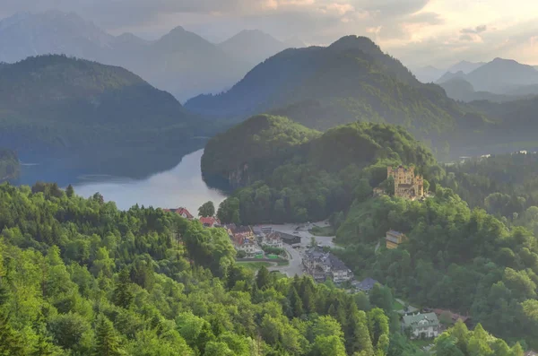 Hohenschwangau castelo e aldeia, em meio a lagos, ao pôr do sol . — Fotografia de Stock