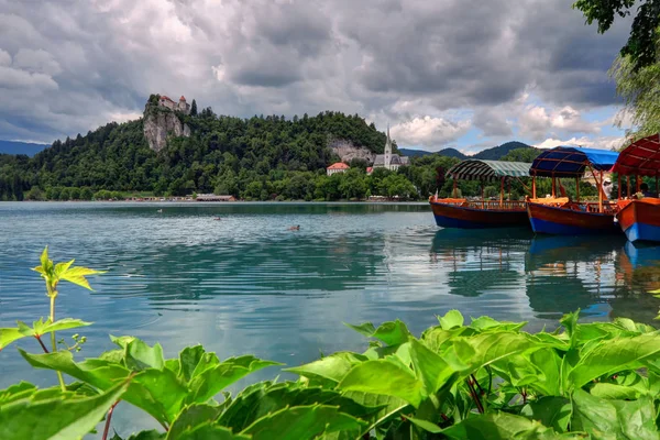 Toeristische boten op de voorgrond, Bled eiland is in de pagina — Stockfoto