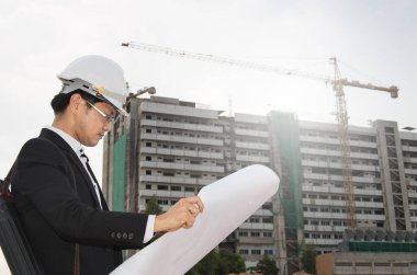 İnşaat alanının planlarını ve planlarını elinde tutan mühendis.