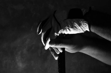 Çubuktaki golf eldiveni giymiş ellerin koyu renkli fotoğrafı. 