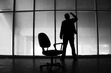 Ofisin camına vuran stresli iş adamının silueti.