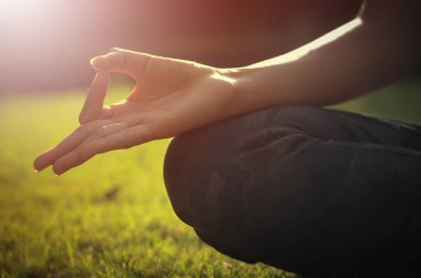 Parkta meditasyon yapan genç bir kadının kısmi görüntüsü